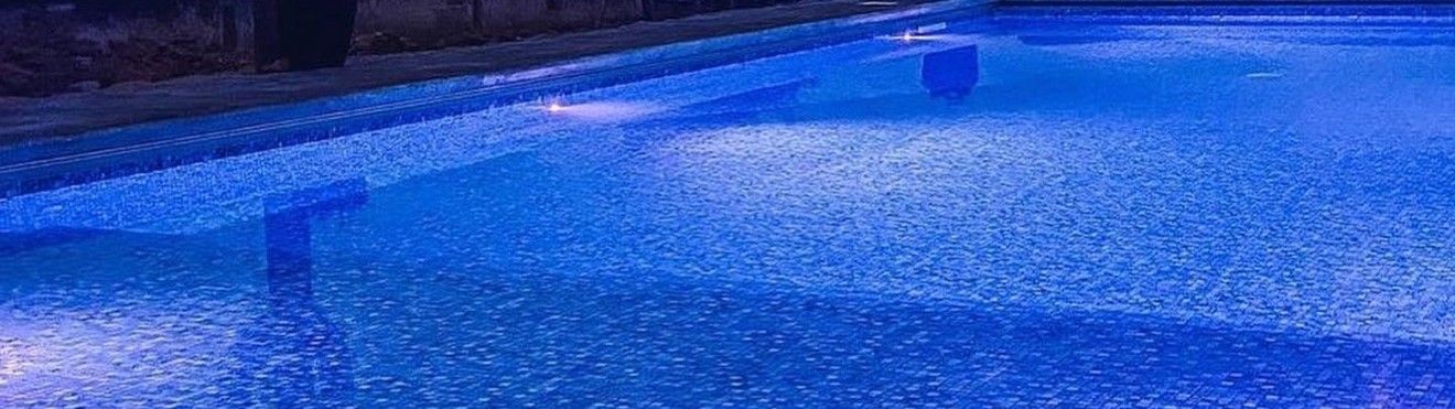 Fattys Pools inground pool glowing blue at night with LED lighting