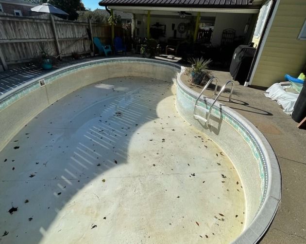 Kidney pool empty and stained with a worn deck before its off-season remodel