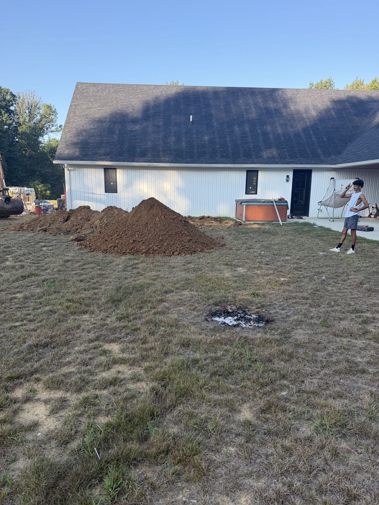 Pool site early in the build with excavated dirt piled alongside the hole