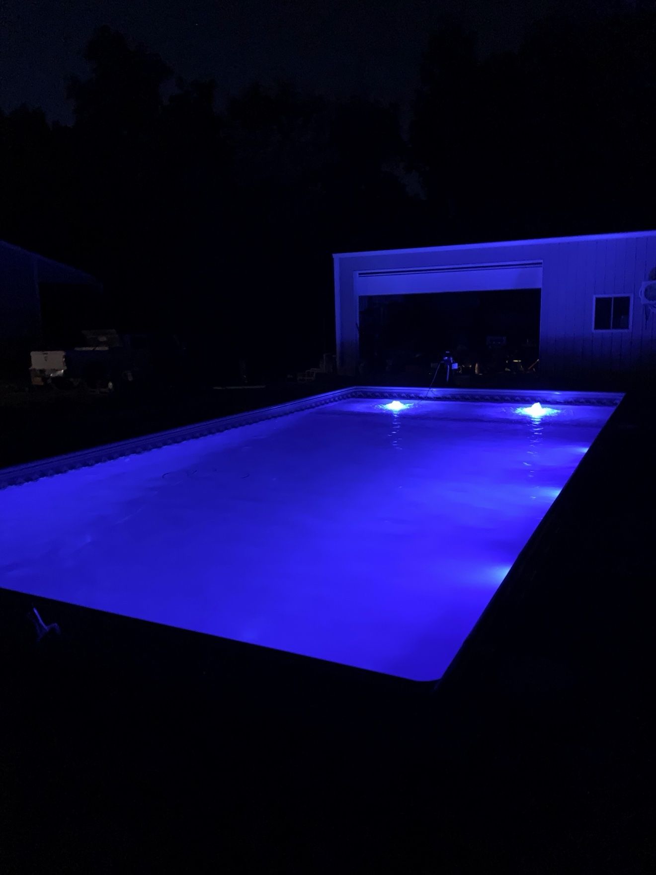 Same pool at night glowing blue and purple from its color LED lights